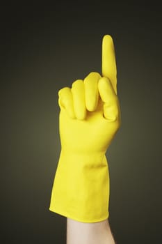 A Hand with a yellow protective rubber glove pointing with a finger