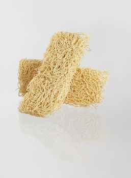 Two blocks of dried asian noodles on reflecting surface.