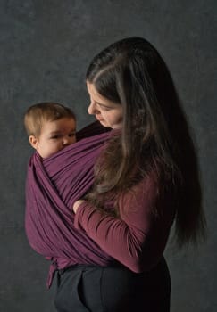 Mother with her daughter in sling, dark background