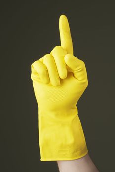 A Hand with yellow protective rubber glove pointing with index finger