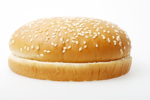 A hamburger bun on a light grey surface.