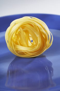 A Bunch of uncooked dried pasta tagliatelle on a blue plate