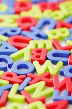 Random colored plastic letters on white background, short depth-of-field.