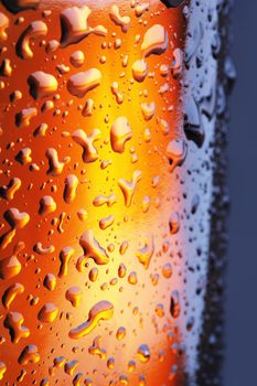 A Brown beer bottle with water beads in closeup.
