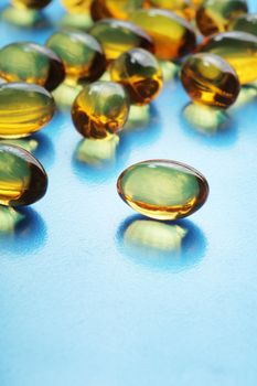 Omega 3 fish oil capsules on blue reflective surface