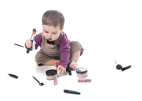 Baby girl playing with cosmetics, white background