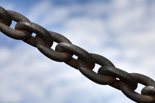 Rusty but strong chain against sky.