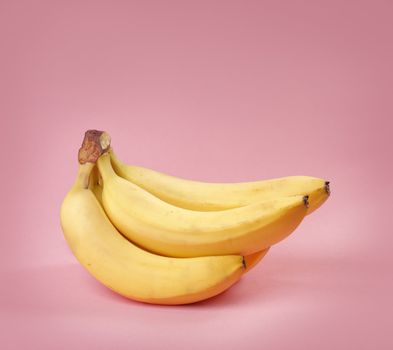 A Bunch of yellow bananas on pink background