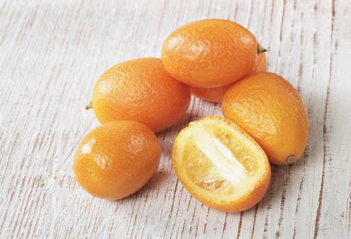 Small orange kumquat fruit on wood.