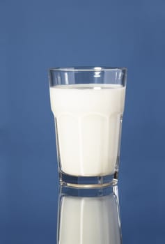 A Glass of milk on blue reflective surface