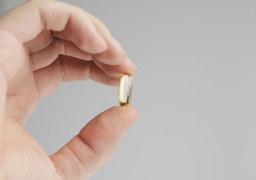 Fingers holding an Omega 3 fish oil capsule