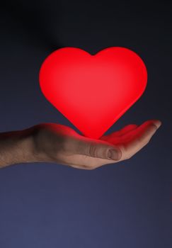 Man holding a red glowing heart shape in his hand.