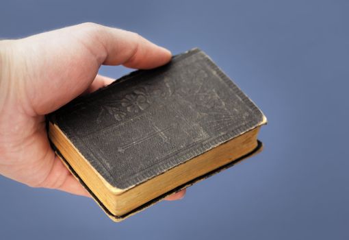 Hand holding a copy of a vintage bible