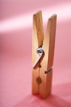 Wooden clothespin on pink surface. Very short depth-of-field.
