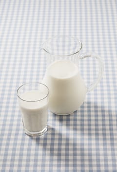A Glass and a pitcher filled with milk