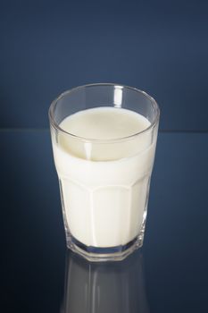 Milk in a glass on blue reflecting background