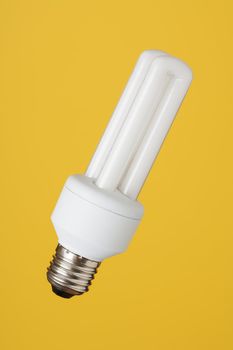 Small energy saving bulb on yellow background