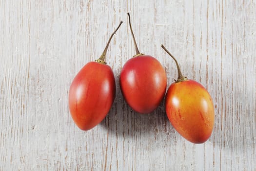 Three Tamarillo fruit (tree tomato) on white wooden background.