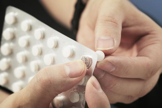 Hands taking out a tablet from a blister pack