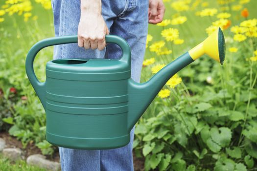 A Man holding a green plastic watering can in his hand.