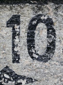 Number 10 painted on stone surface, worn and weathered.