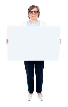 Smiling old lady holding blank whiteboard. Full length portrait