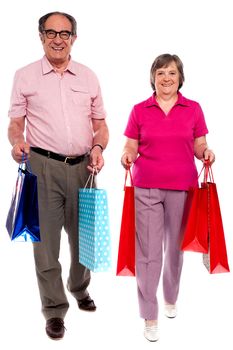 Husband and wife holding shopping bags and walking towards camera