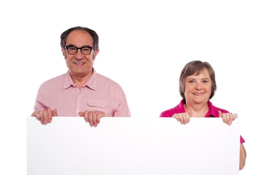 Aged couple displaying blank billboard isolated over white background