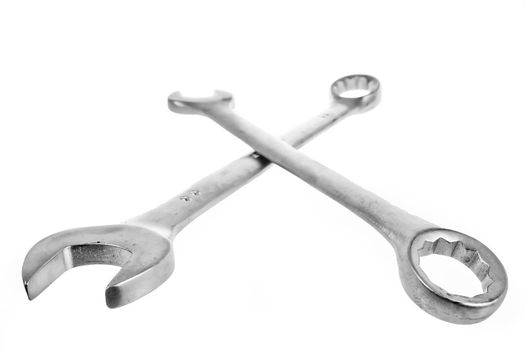 Two crossed wrenches on a white lie