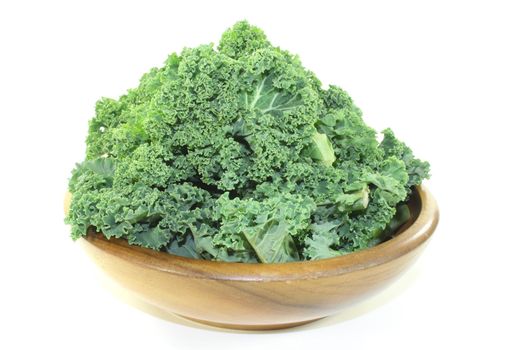 fresh green kale in a wood bowl on light background