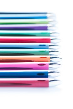 Line of many colored pens on a white background