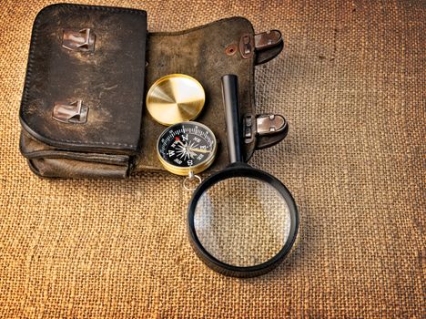 Vintage background with  wallet, compass and magnifier on the sacking