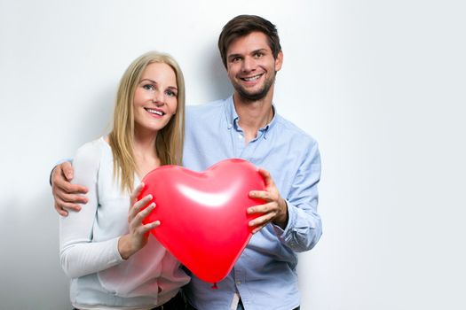 Young couple smiling and holding a red heart