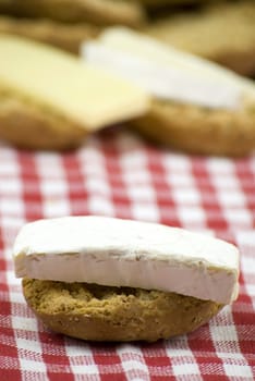 freshly baked crisp bread rolls with brie cheese over white and red cloth fabric