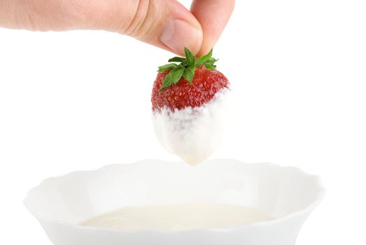 Hand dip strawberry in cream on white