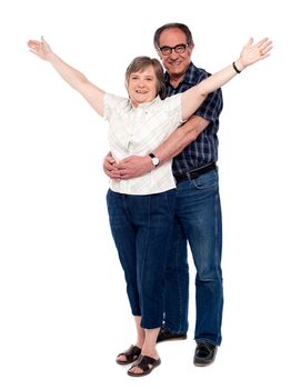 Man hugging his wife from behind while woman standing with arms wide open