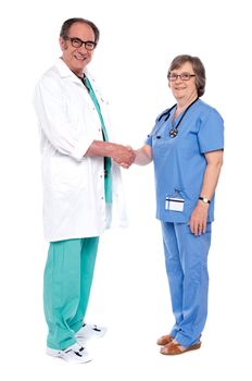 Full body portrait of two senior medical persons shaking hands isolated on white background