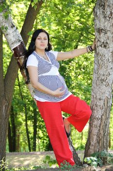 The young pregnant girl walks in park