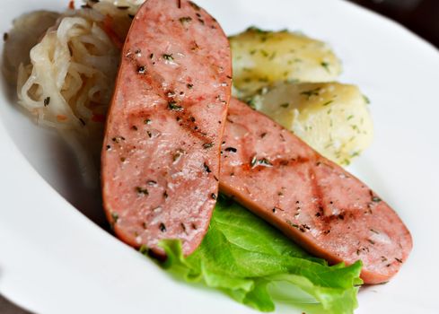 fried sausages in a white plate with lettuce.