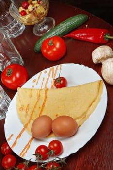 pancakes on a plate with vegetables and egg.
