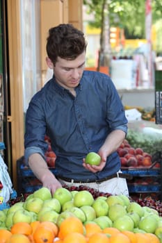 Young handsome customer choosing fruits at grocery store