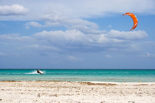 A kitesurfer gliding at high speed around the beach Cinta, Sardinia