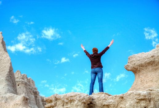 Woman with raised hands against blue sky