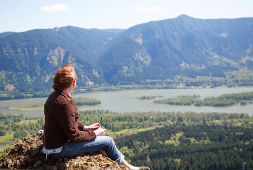 Woman sits at the top of a cliff relaxing