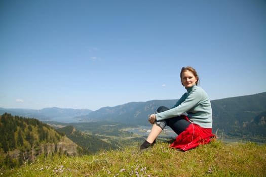 Woman seats at the top of a cliff relaxing