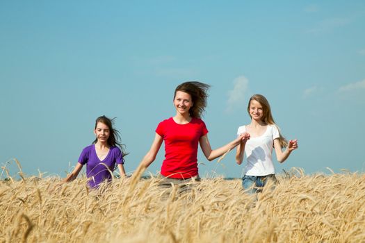 Teen girls running at the wheat field in sunny day