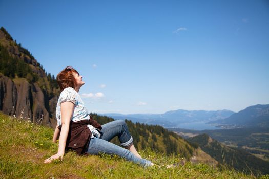 Woman sits at the top of a cliff relaxing