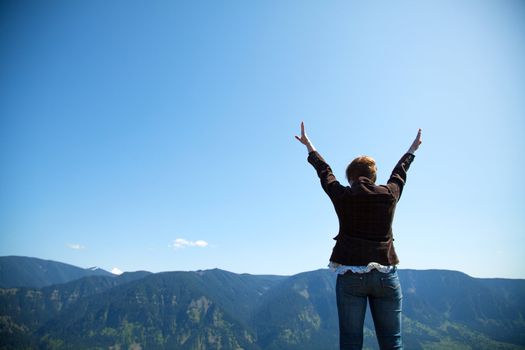 Woman with raised hands against blue sky