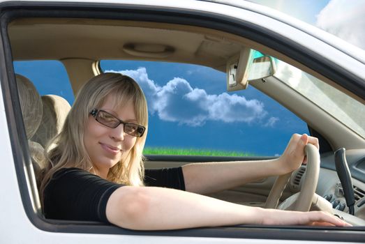 Pretty young woman driving car on nature background