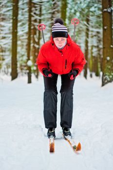 Happy girl posing on skis in the winter woods.